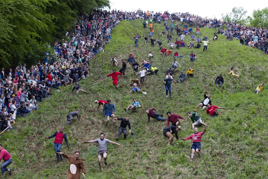 Competitors tumble down Coopers Hill in pursuit of a round Double Gloucester cheese during the annual cheese rolling and wake near the village of Brockworth near Gloucester in western England on May 26, 2014. With a disputed history dating back to at least the 1800s, the annual Cooper's Hill Cheese Rolling involves hordes of fearless competitors chasing an eight pound Double Gloucester cheese down a steep hill. The slope has a gradient in places of 1-in-2 and in others 1-in-1, its surface is very rough and uneven and it is almost impossible to remain on foot for the descent. The winner of the race down the hill wins the cheese.AFP PHOTO / JUSTIN TALLISJUSTIN TALLIS/AFP/Getty Images ORG XMIT: 1095